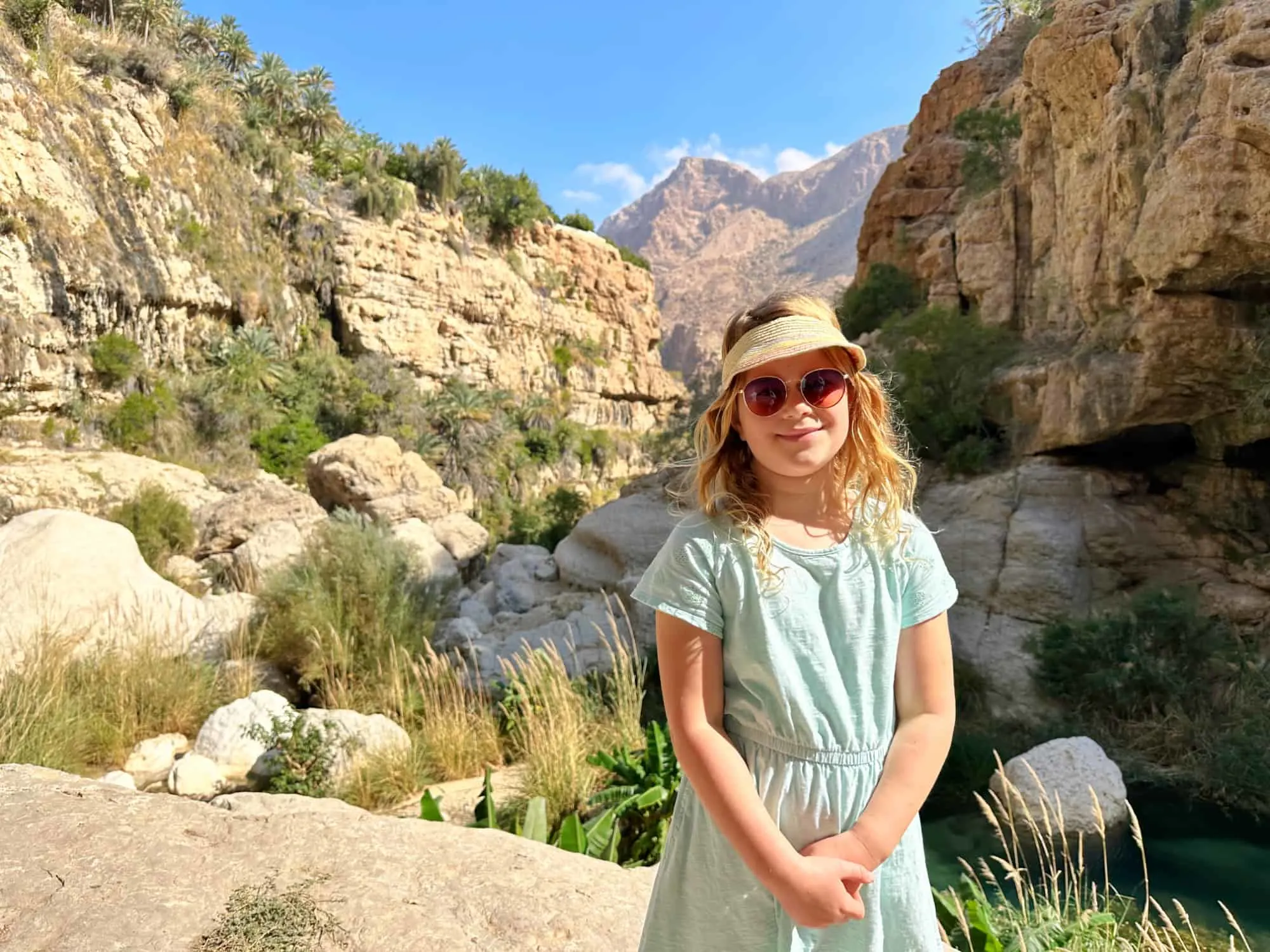 Our seven-year-old daughter in Wadi Tiwi canyon just before the pools where we swam. Behind her is a rocky canyon with plenty of trees and greenery growing