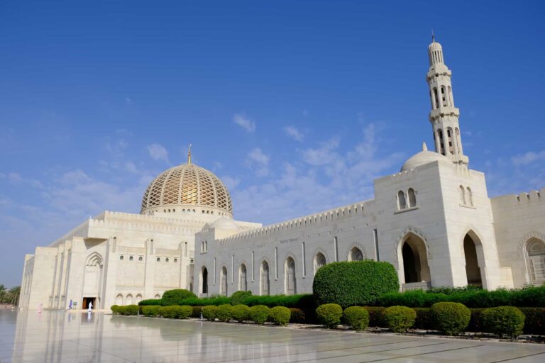 Exterior of the marble and sandstone mosque with rows of bushes in front