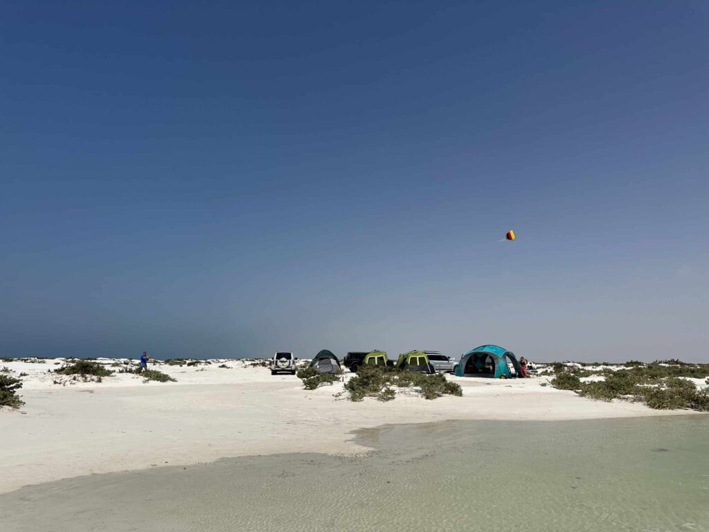 Tents pitches on white sand beach beside a tropical lagoon