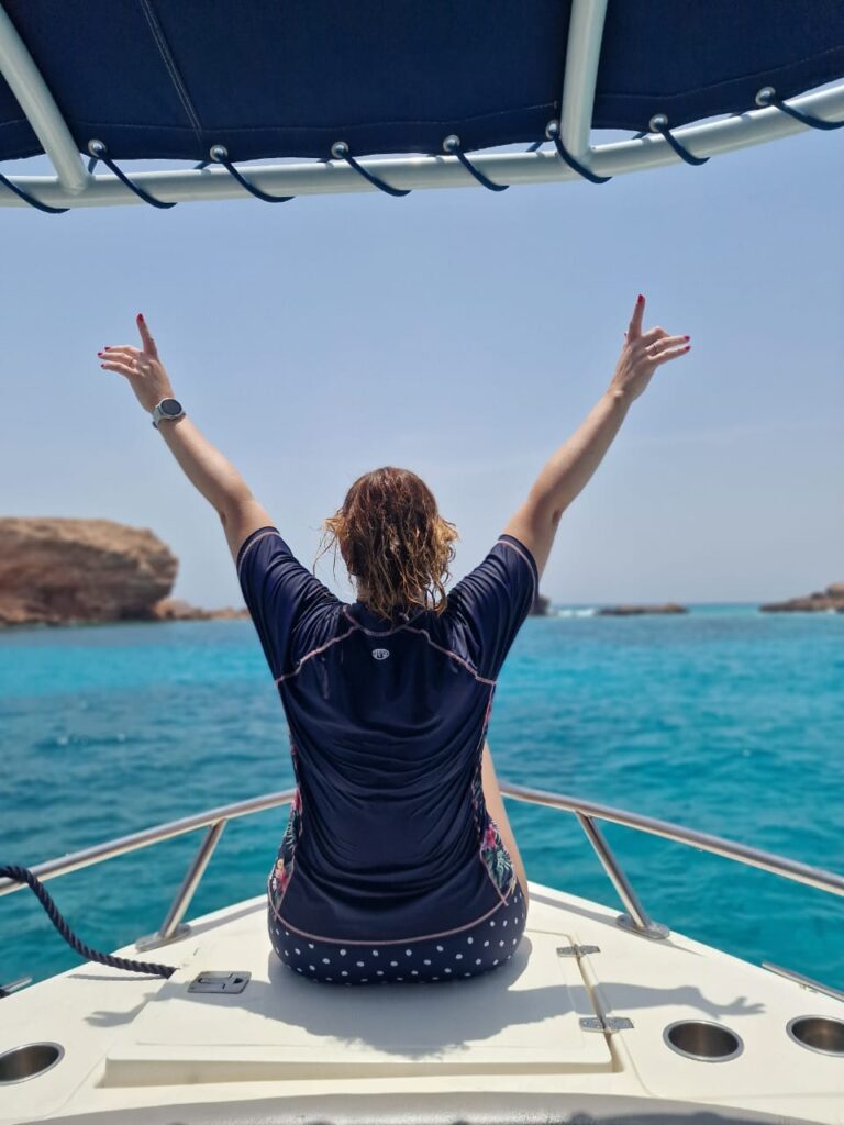 Claire sat on the front of a boat looking out over the turquoise water surrounding the Daymaniat Islands
