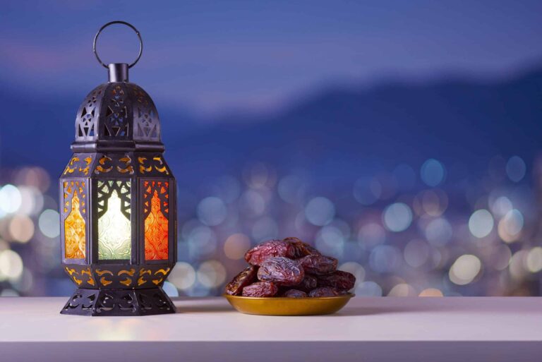 Holy month of Ramadan concept. Righteous Muslim Lifestyle. Ramadan lantern (Fanous), dates.. Mountains and City lights in bokeh blurred background.
