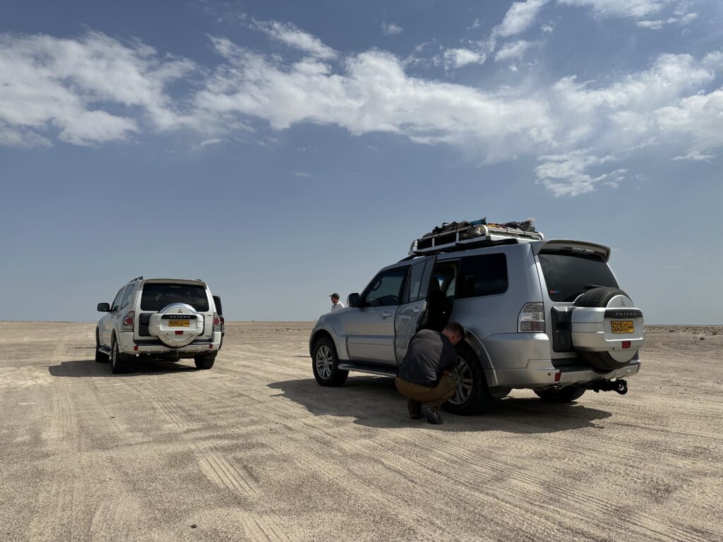 Mr Tin Box letting air out of the rear tyre of our Pajero 4x4 on the salt flats before Barr al Hickman