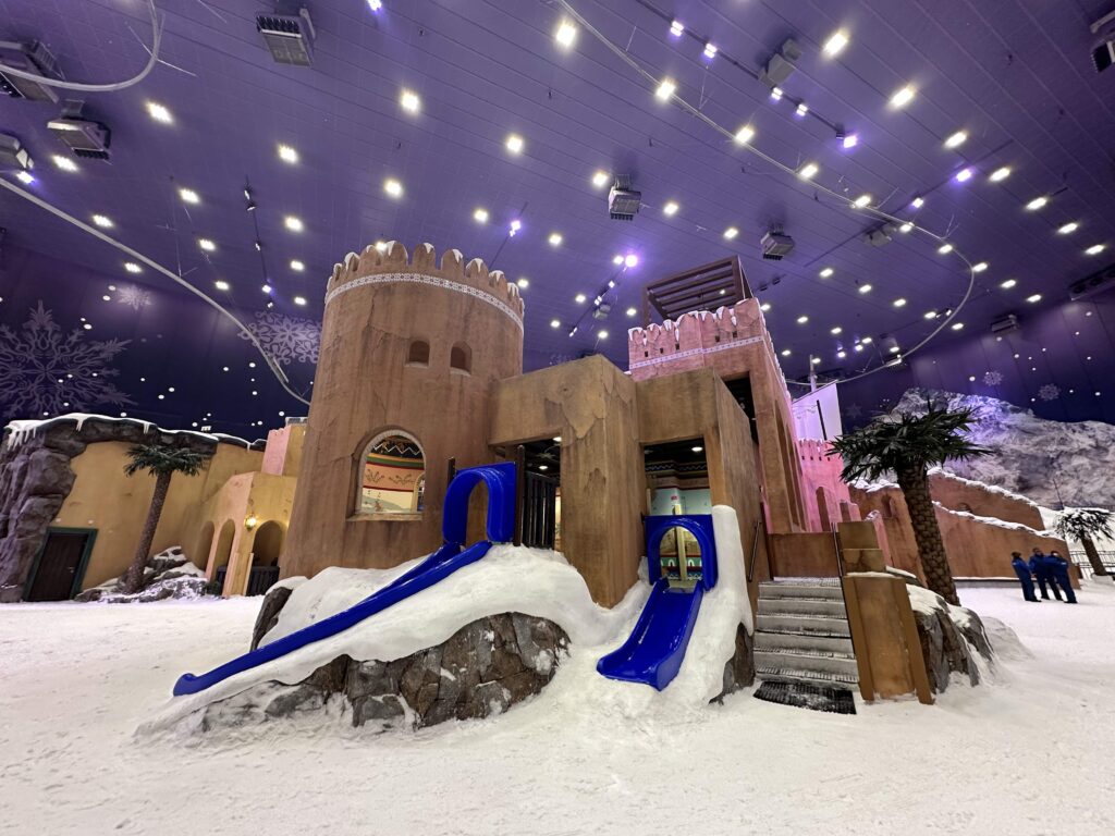 Two children's slides coming out of the side of a mock castle in Snow Oman