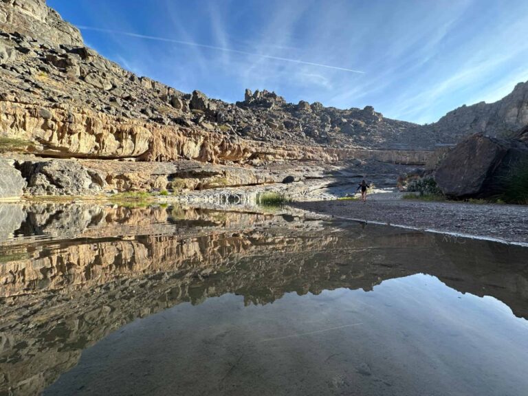 Reflections of the walls of a valley in still water in Wadi Damm, one of the incredible things to do in Oman