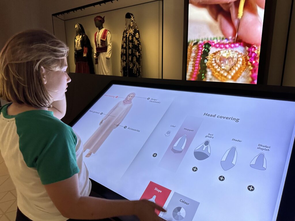 Child plays on interactive game screen to pick the traditional clothes for an Omani woman