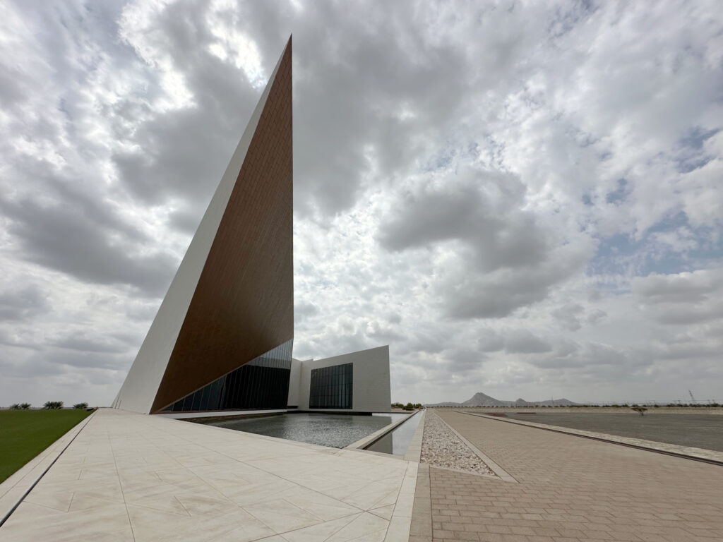 Geometric tower of Oman Across the Ages Museum rising into the sky above a reflection pool