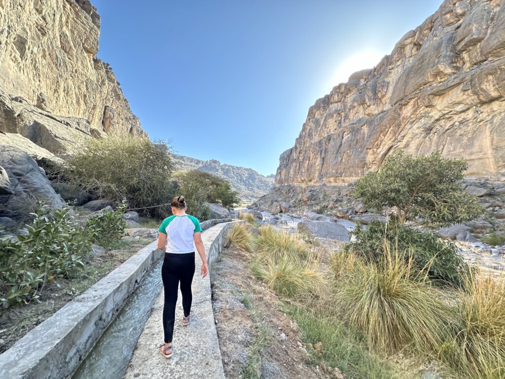 Our daughter walks beside a flaj irrigation channel in Wadi Damm in the Hajar Mountains