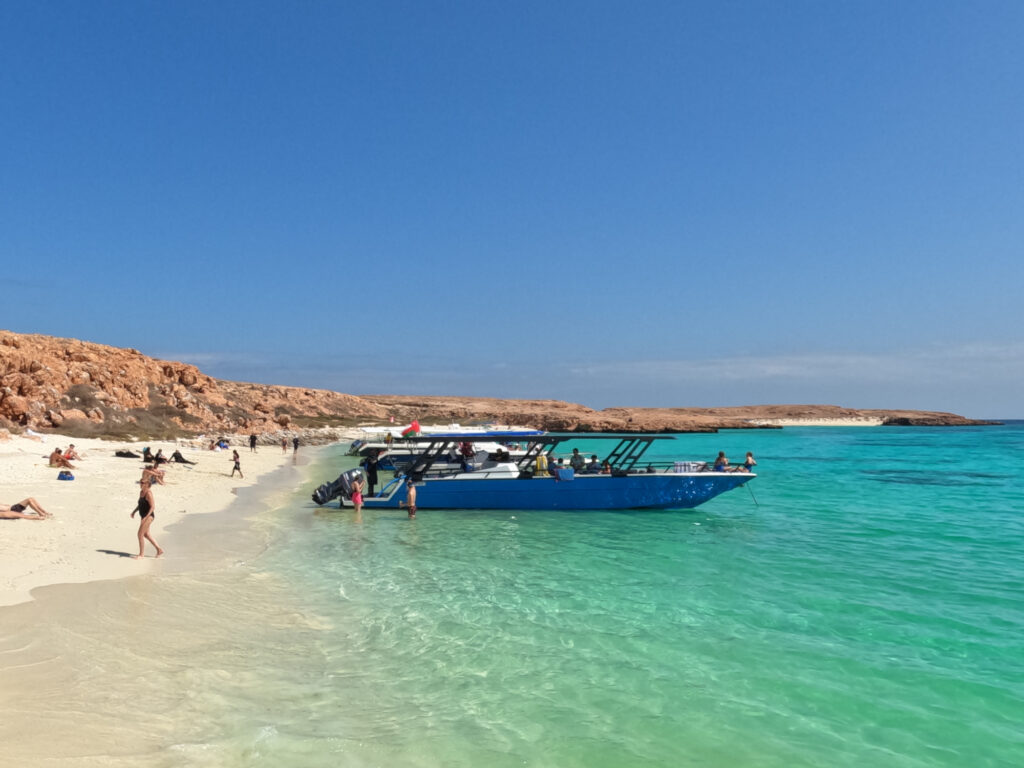The Daymaniat Shells boat moored at a beach in the Daymaniat Islands. The sea is clear and the sand is white
