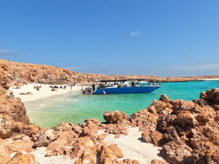 Daymaniat Shells boat on the beach at the islands. Visitors relax on the beach