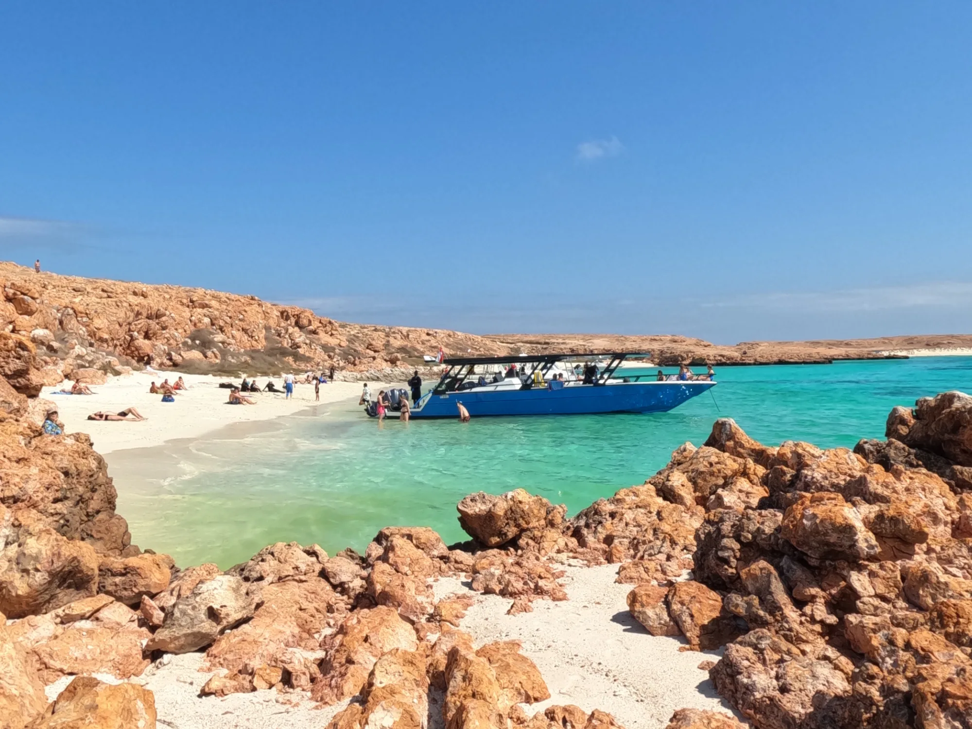 Daymaniat Shells boat on the beach at the islands. Visitors relax on the beach