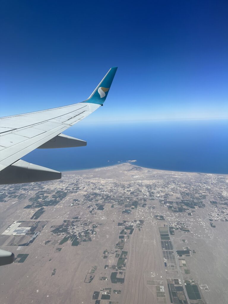 The wing of an Oman Air place over the Oman coastline at Suwadi
