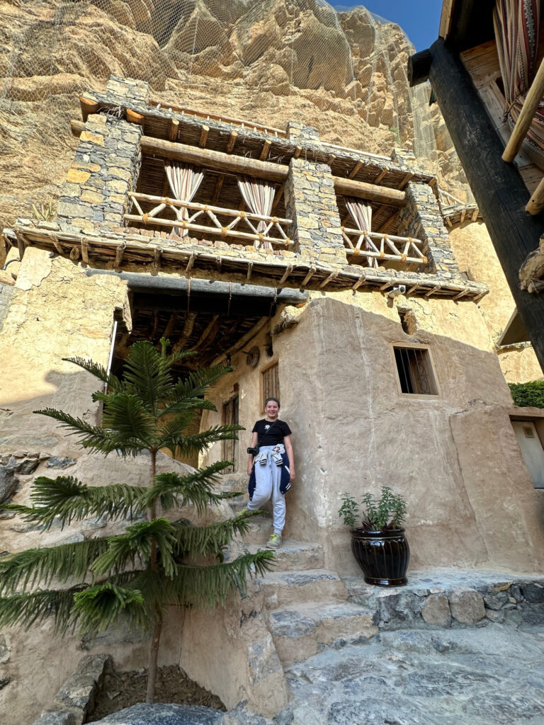 Our 11-yar-old daughter stands at the door way below the Al Arsha Suite which is built into the cliffside