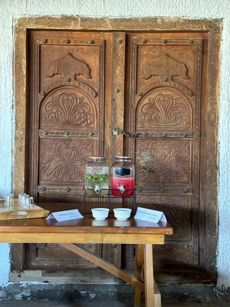 Juice ad water dispensers in the restaurant with an ornately carved Omani door behind