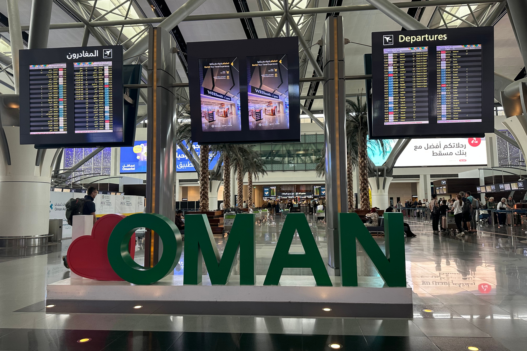 Departure boards and I heart Oman sign in Muscat airport