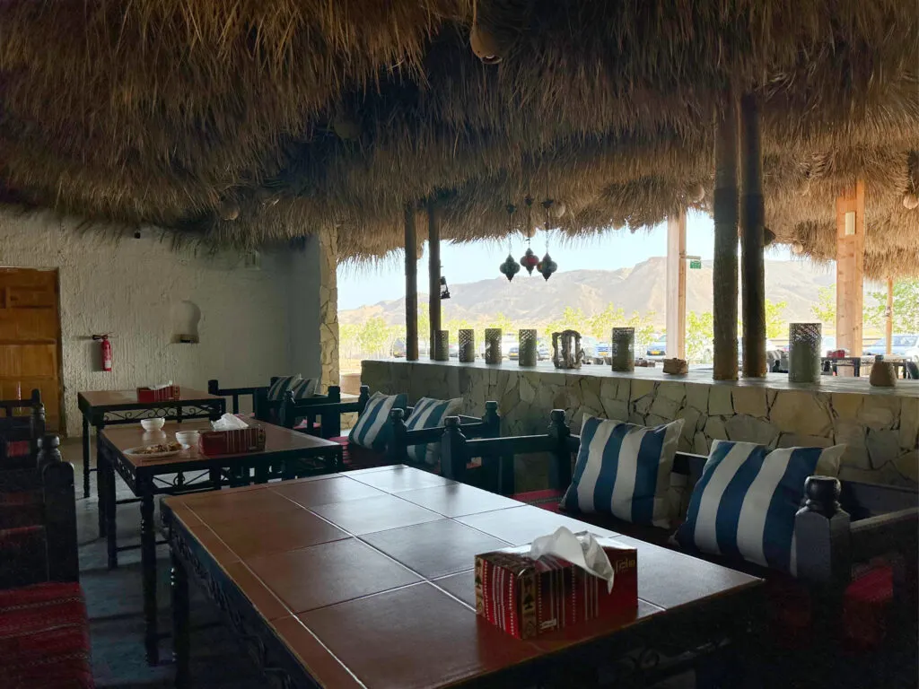 The restaurant at SAMA Ras Al Jinz Resort. There are tables and benches and an open wall through which you can see a view of mountains