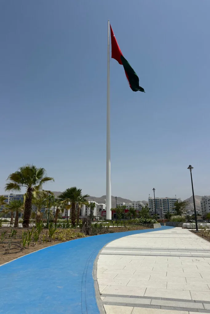 The Muscat flagpole flying an Omani flag. The blue coloured cycle path is in the foreground