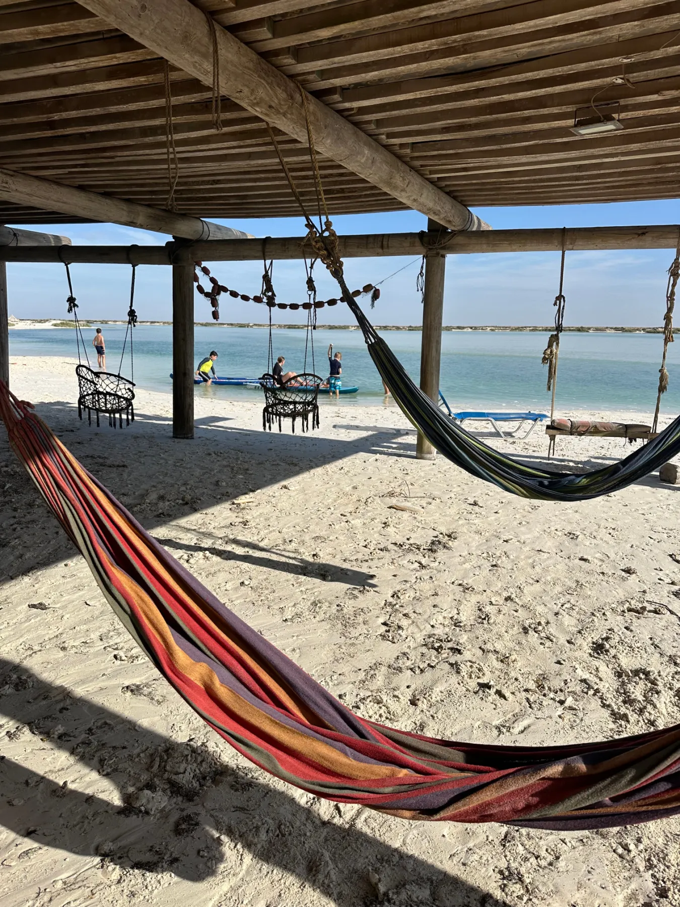 Two hammocks slung under the whale station at Whales Head Camp. There's views of the lagoon in the background