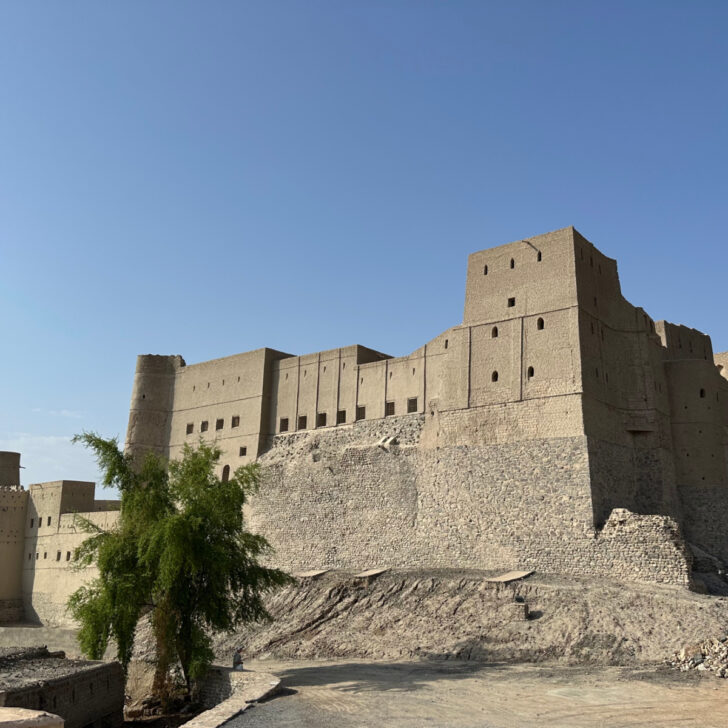The sand coloured exterior of Bahla Fort in a mountain oasis