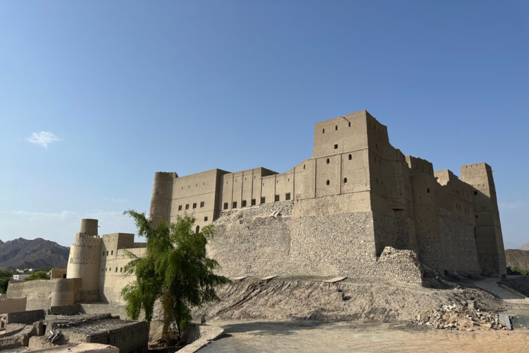 The sand coloured exterior of Bahla Fort in a mountain oasis