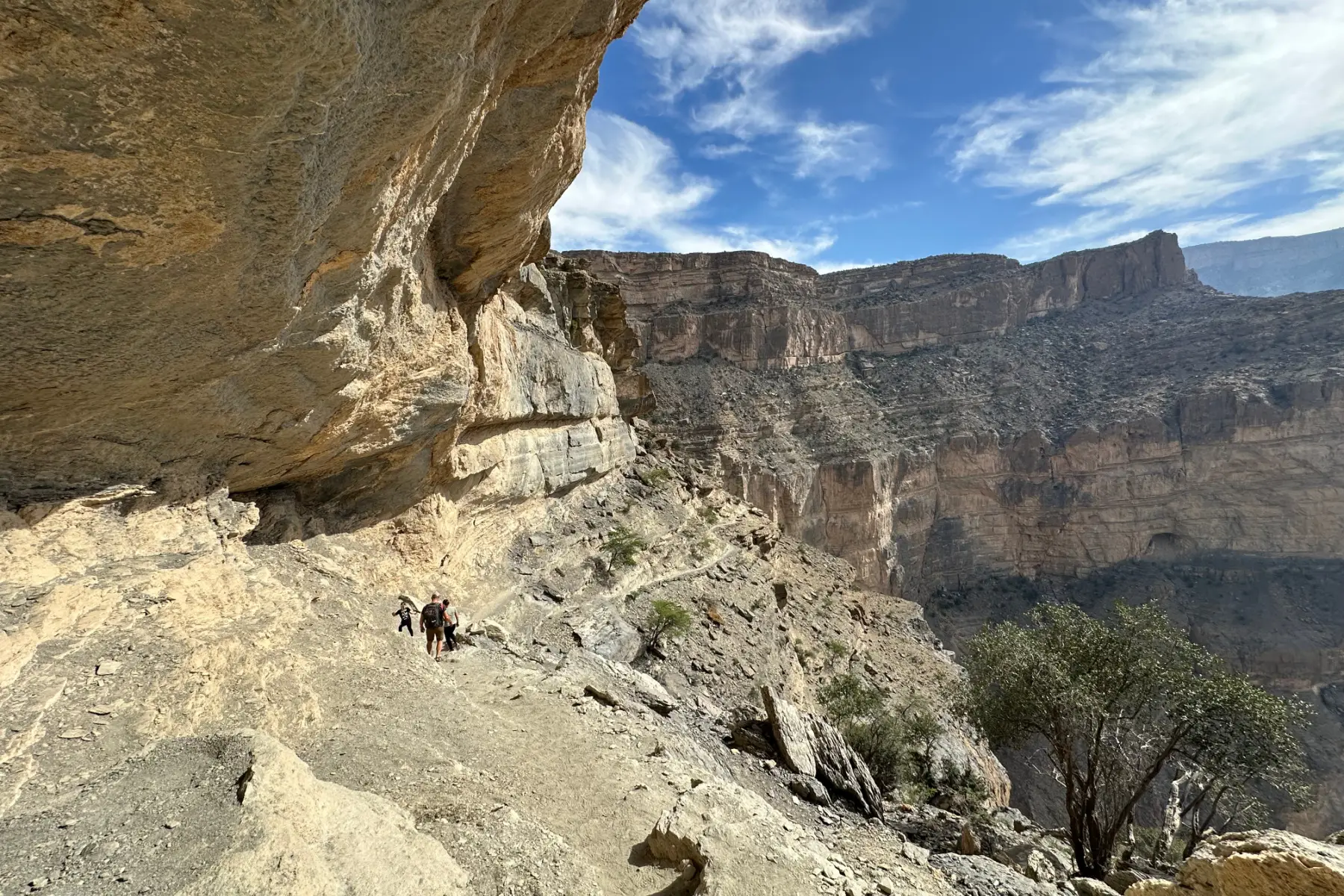 A limestone overhang on the Jebel Shams Balcony Walk. My family can be seen looking tiny on the path below