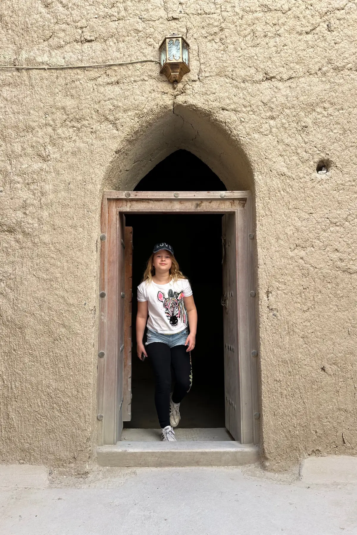 My daughter walking through an arched doorway in Bahla Fort
