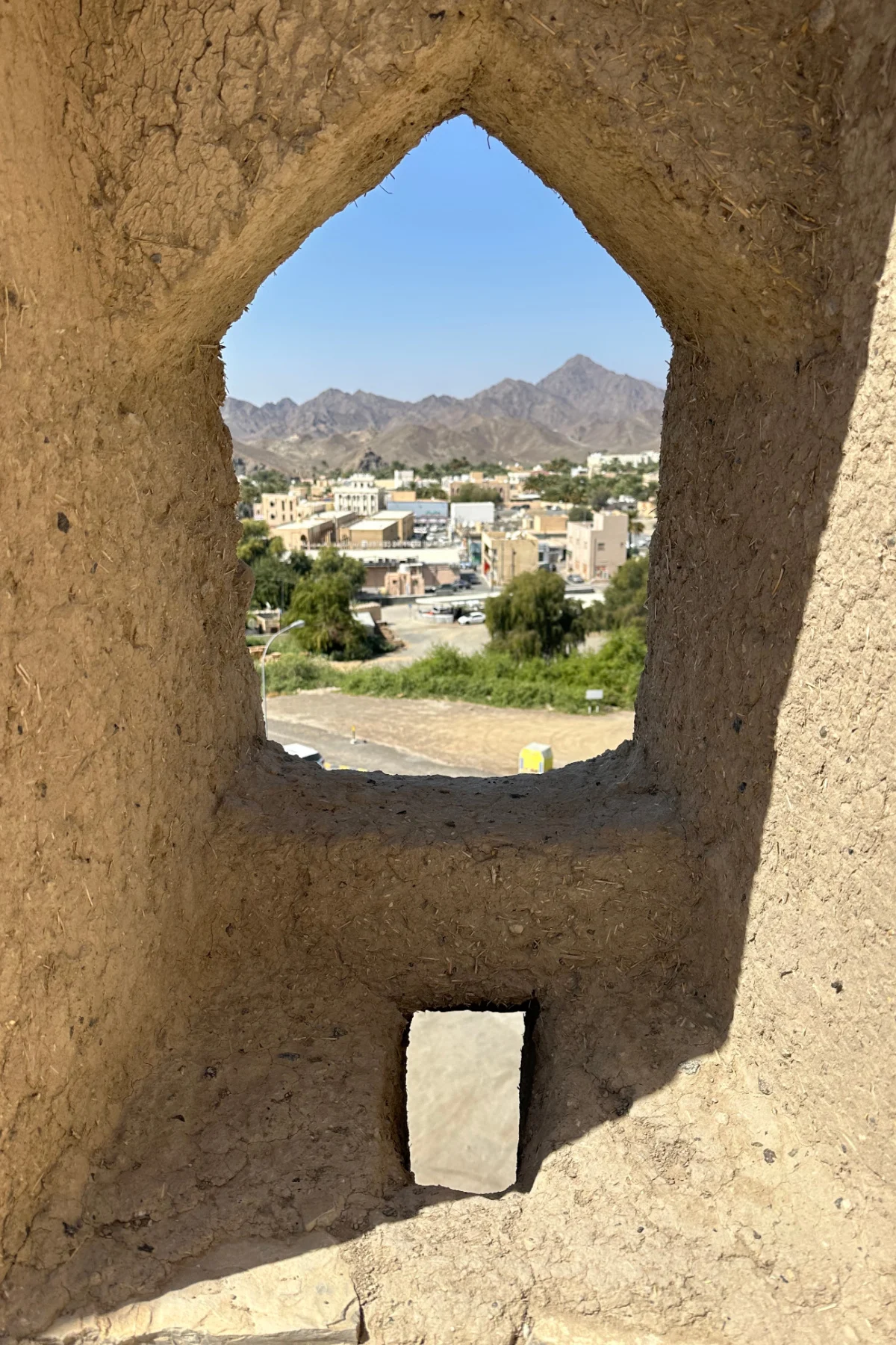 A small window and loop hole rifle hole in the outer fort wall. Through the window its possible to see the oasis of Bahla