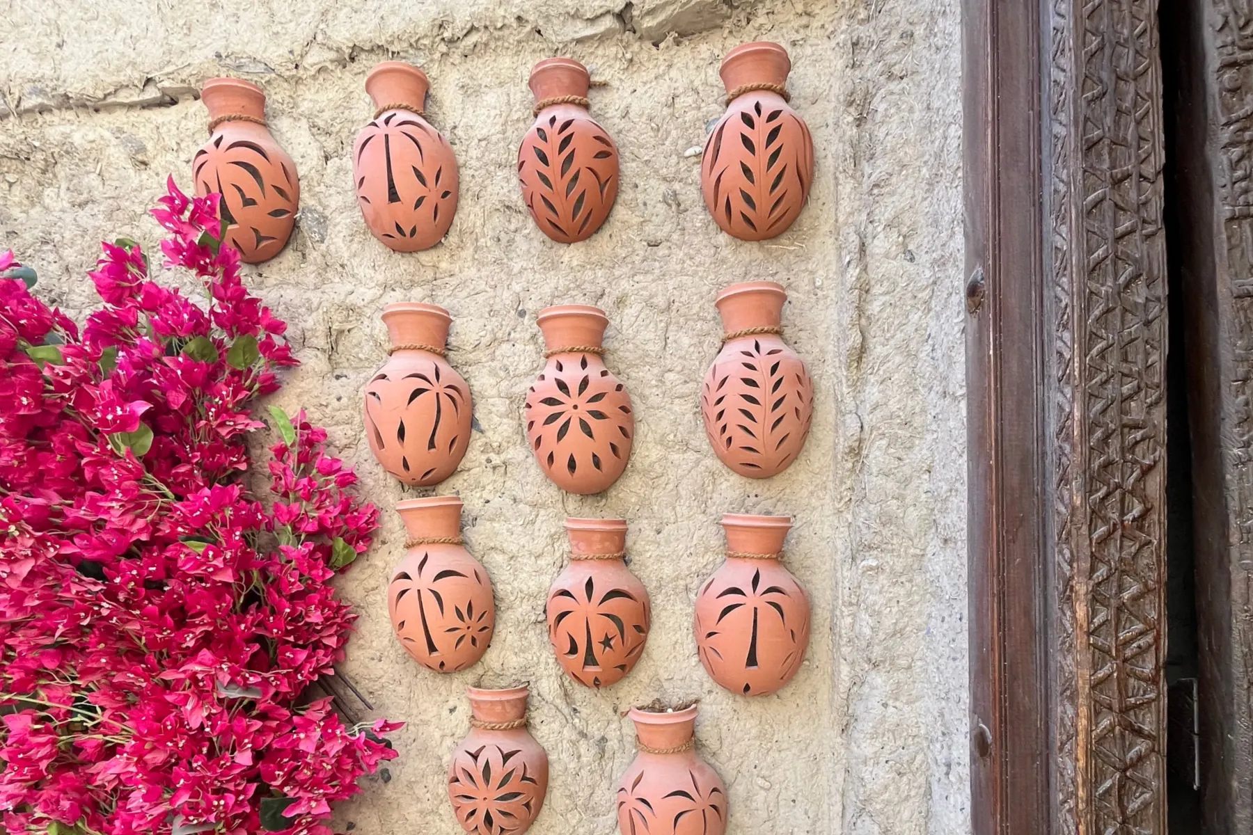 A white wall decorated with orange Omani pots