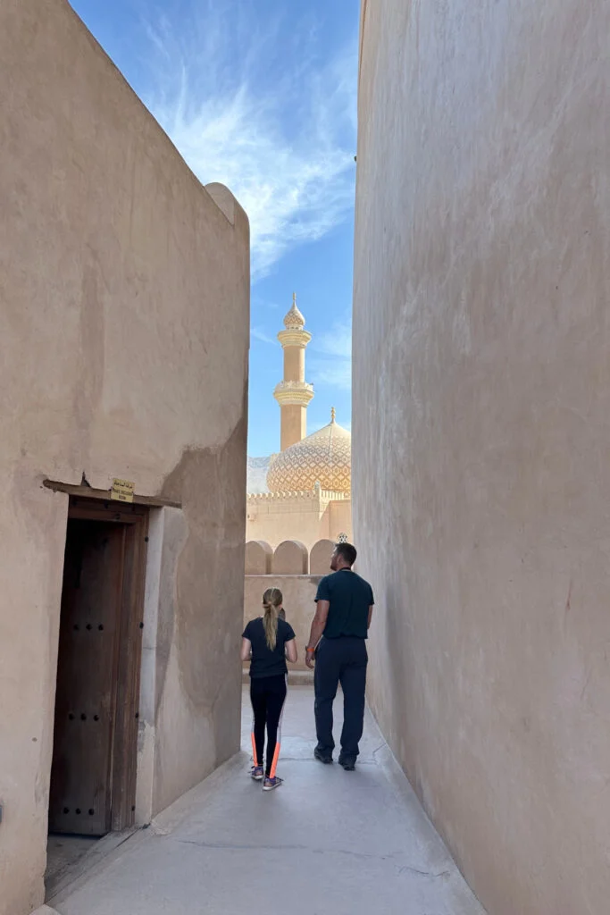 My husband and daughter exploring the roof of Nizwa Castle. The mosque dome and minaret can be sen beyond them