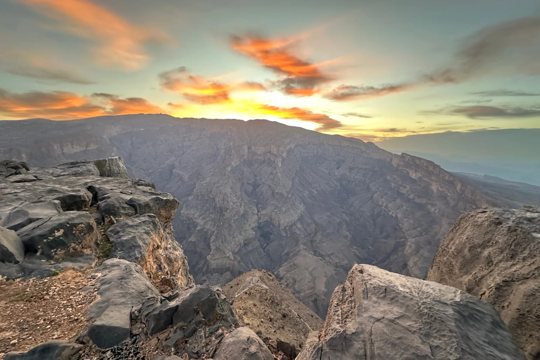 Orange and purple clouds over Jebel Shams mountain as the sun begins to rise