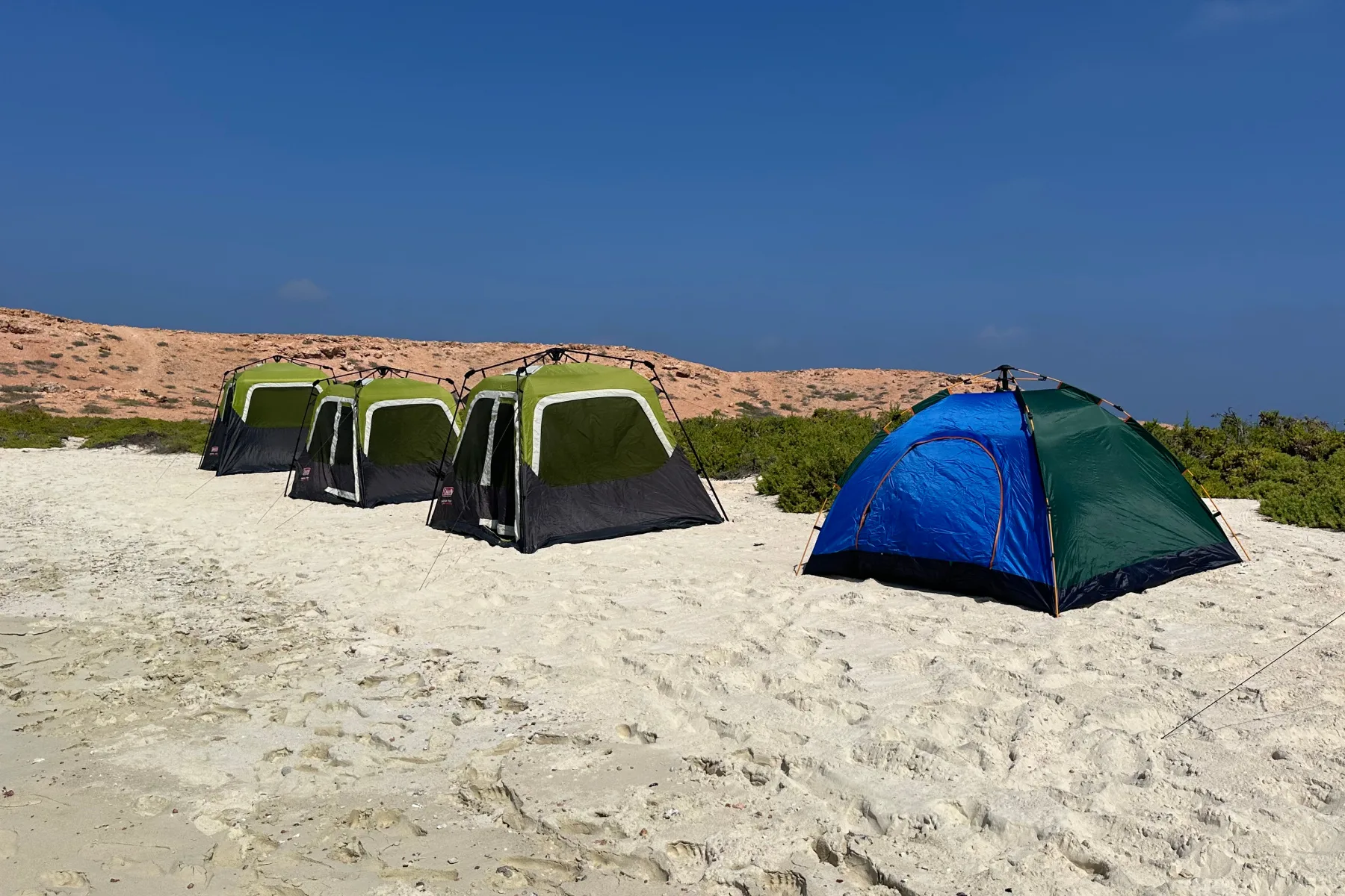 Four tents pitched on a sandy beach on the islands
