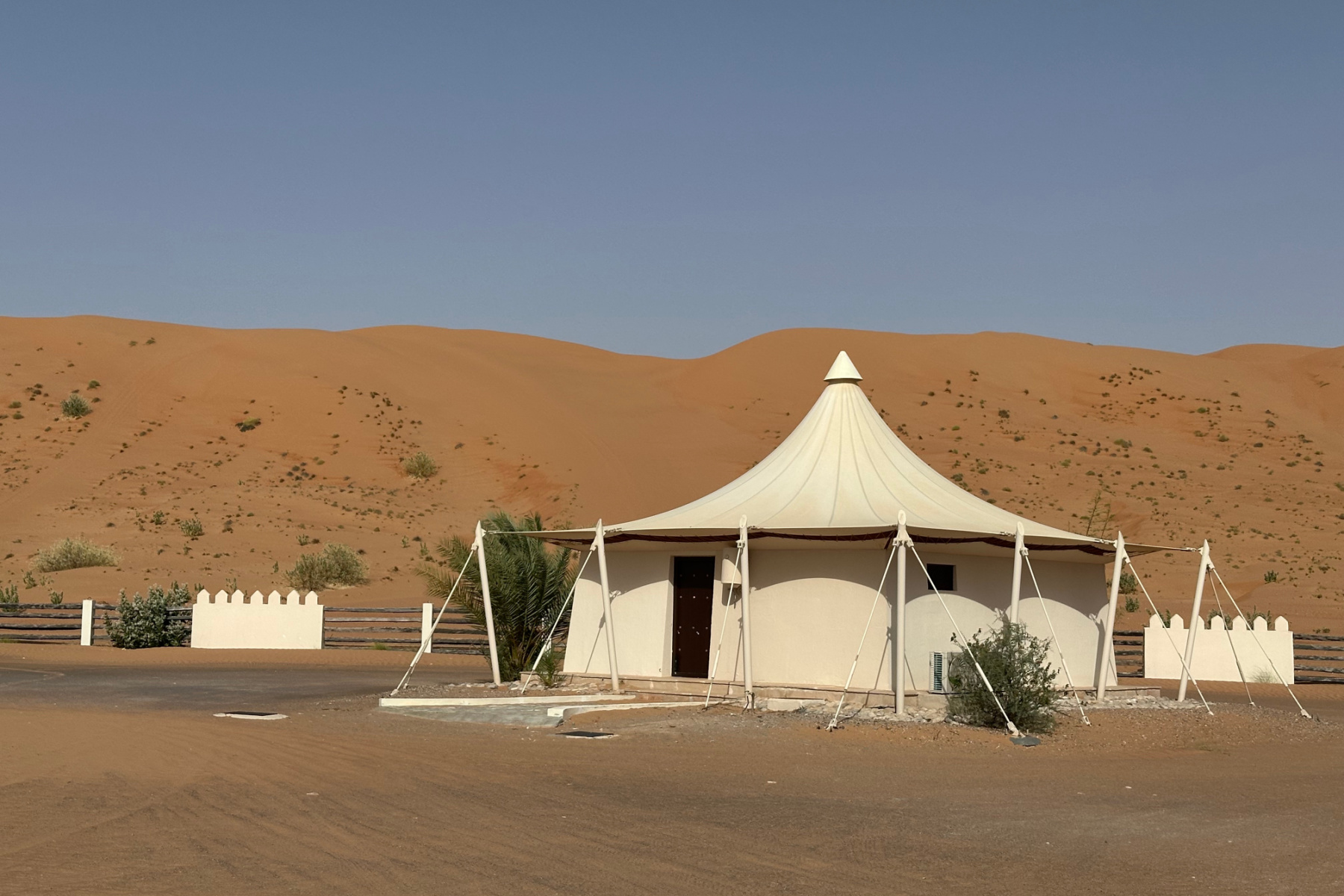 A villa with tented roof at Desert Nights Resort. AS sands dune stands behind it