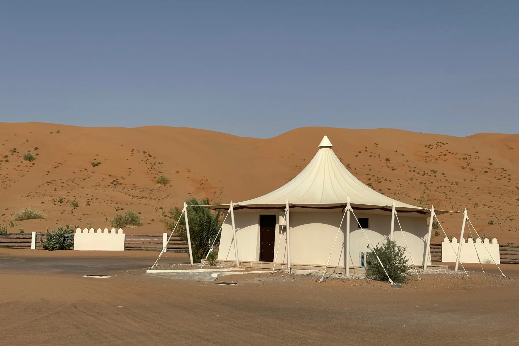 A villa with tented roof at Desert Nights Resort. AS sands dune stands behind it