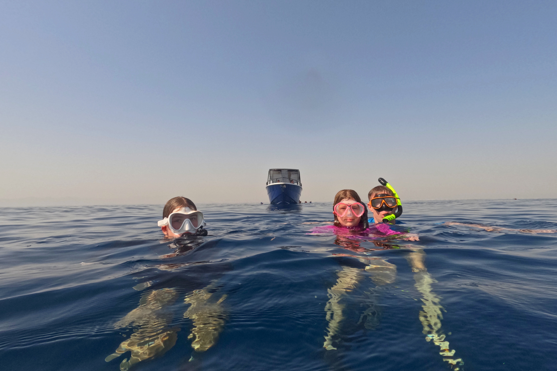 My family in the water with snorkel masks on. The are in front of the Daymaniat Shells boat called the Blue Monster