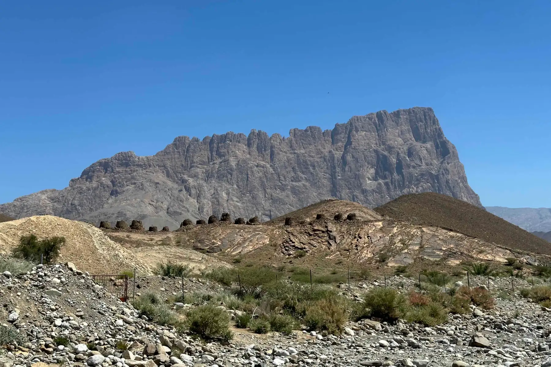 Dark dots on a hill are the beehive tombs in front of Jebel Misht