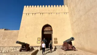 My family walking between two canons at the entrance to Nizwa Fort