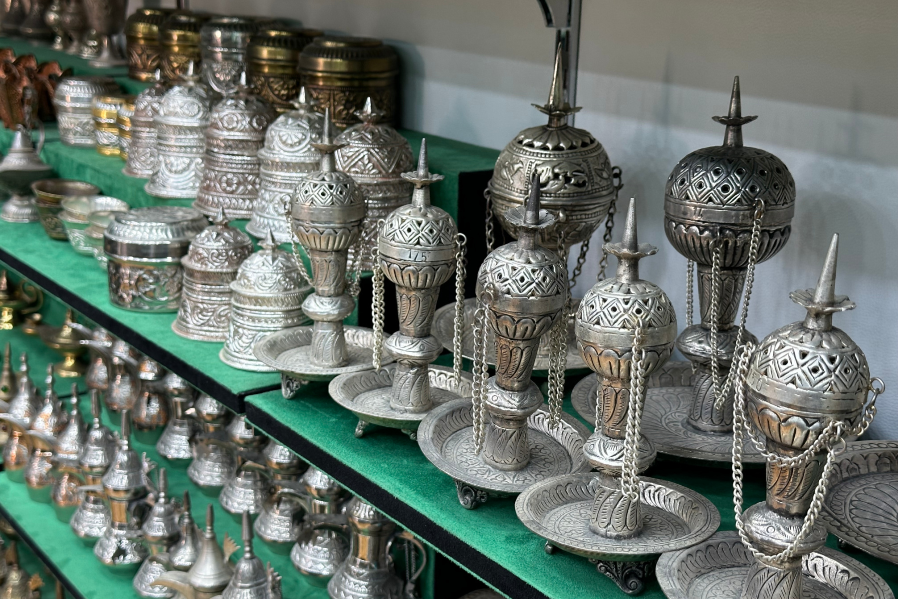 Silver incense burners lined up on a shelf in a souq shop