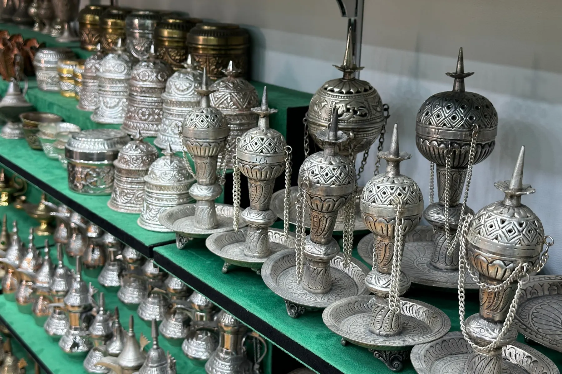 Silver incense burners lined up on a shelf in a souq shop