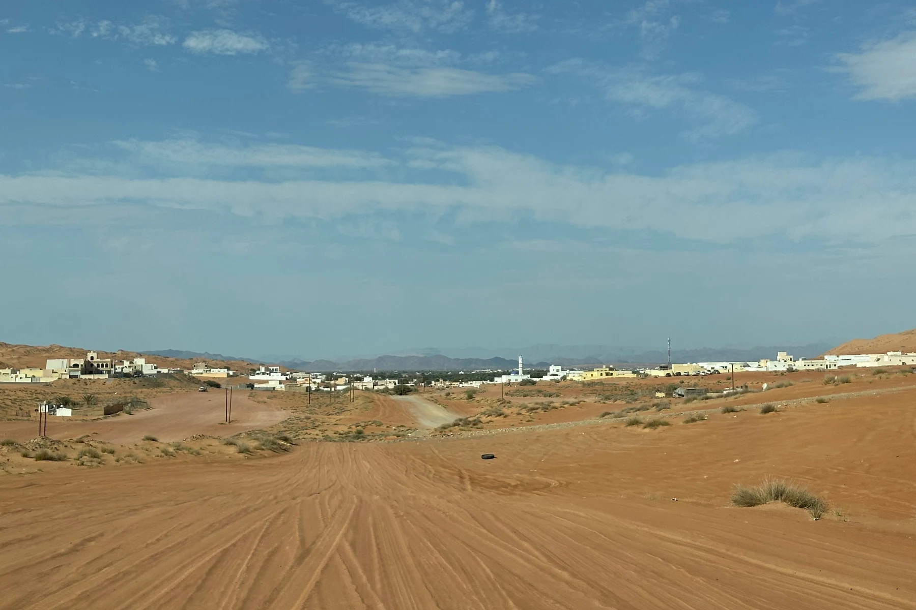 The town of Al Raka comes into view at the end of the Bedouin road. Behind it are the Hajar Mountains