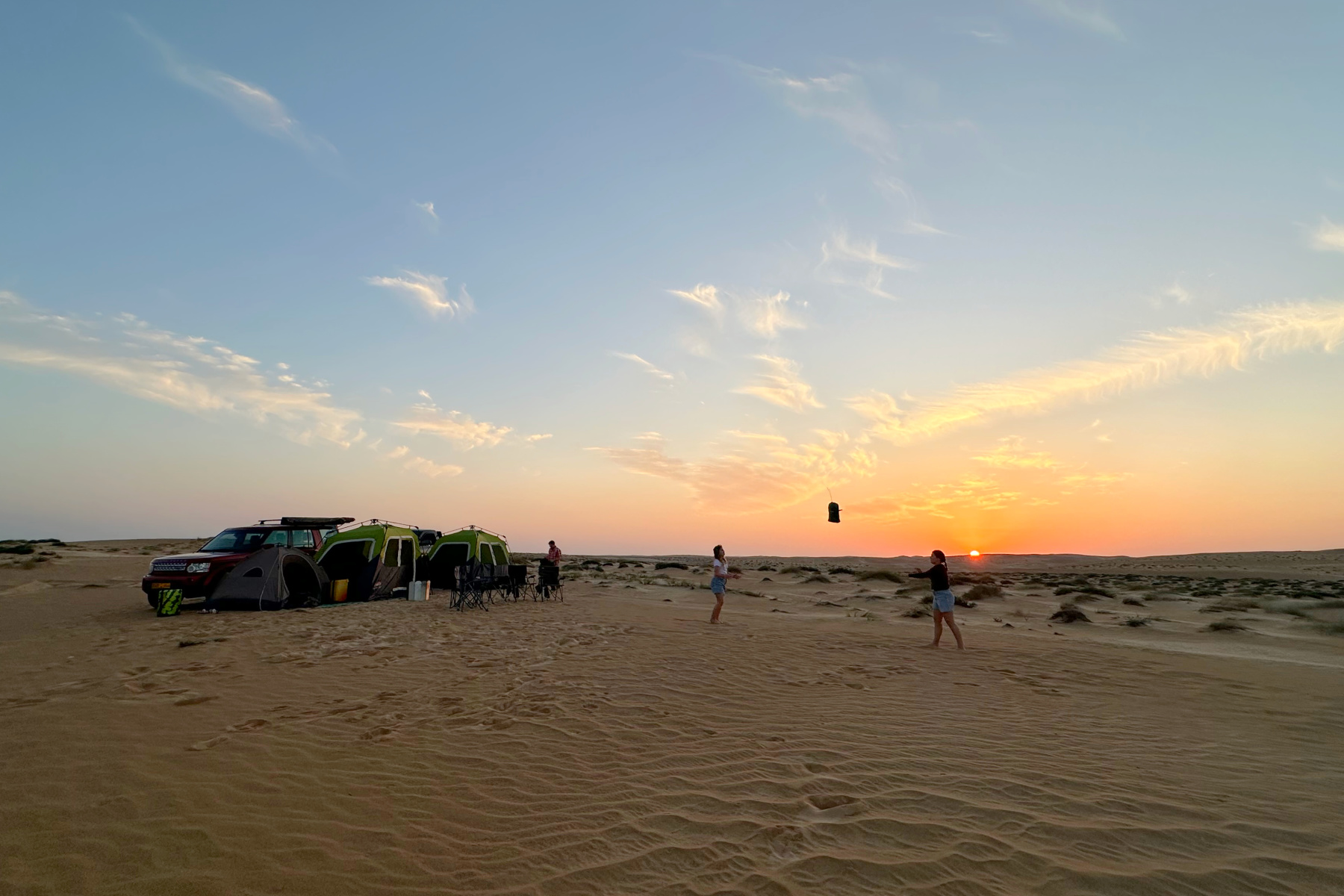 Our camp on the edge of the desert at the bottom of Wahiba Sands. The sun is setting, my children are playing and our tents are pitched beside our cars