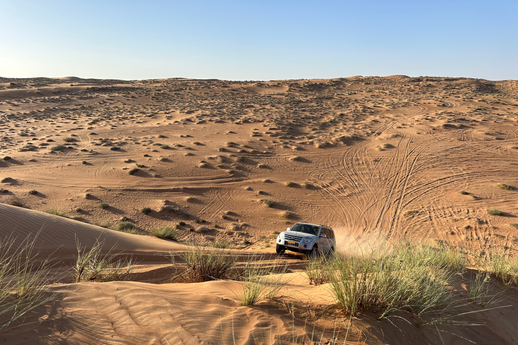 Our car driving up a tall sand dune