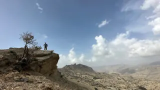My husband standing on an outcrop on Jebel Akhdar looking at a view over the Hajar Mountains