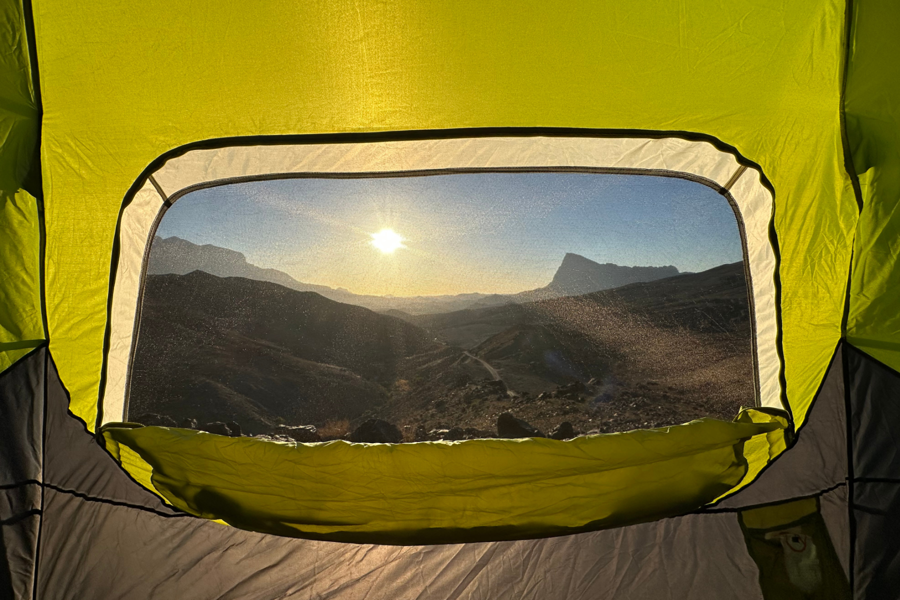 A view out of the mesh of our tent window looking toward the sun rising over Jebel MIsht near Wadi Damm