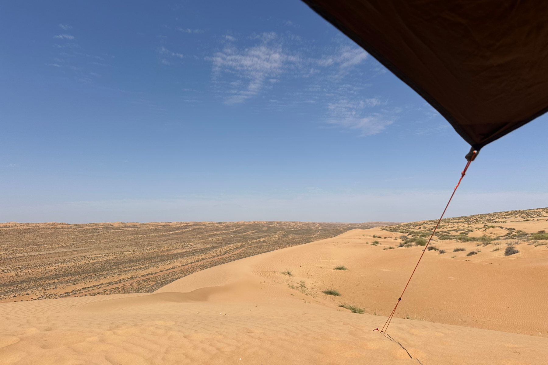A corner of our tarp canopy can be seen in front of a view from the top of a sand dune where we stopped for lunch