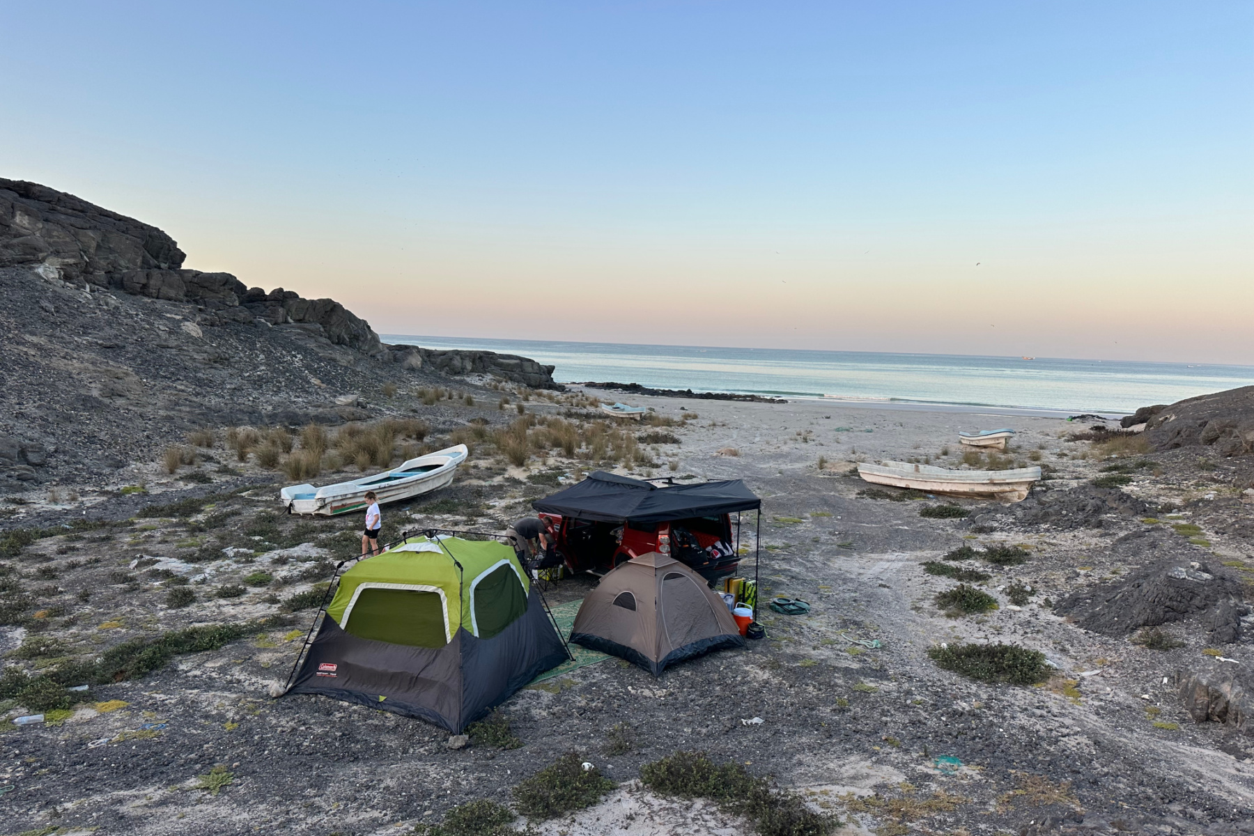 Our car and tents pitched in a rocky cove on the coast at Ras Madrakah. There are fishing boats abandoned among the rocks