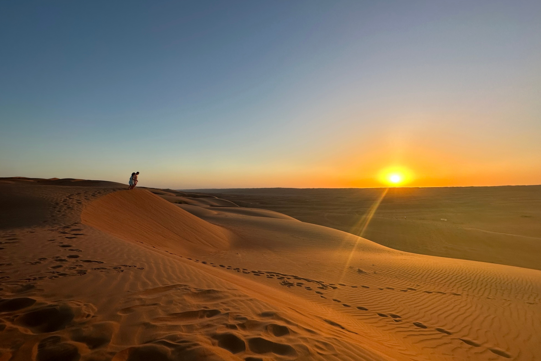My daughters at the top of a sand dune waiting to run down. The sun is setting in Wahiba Sands