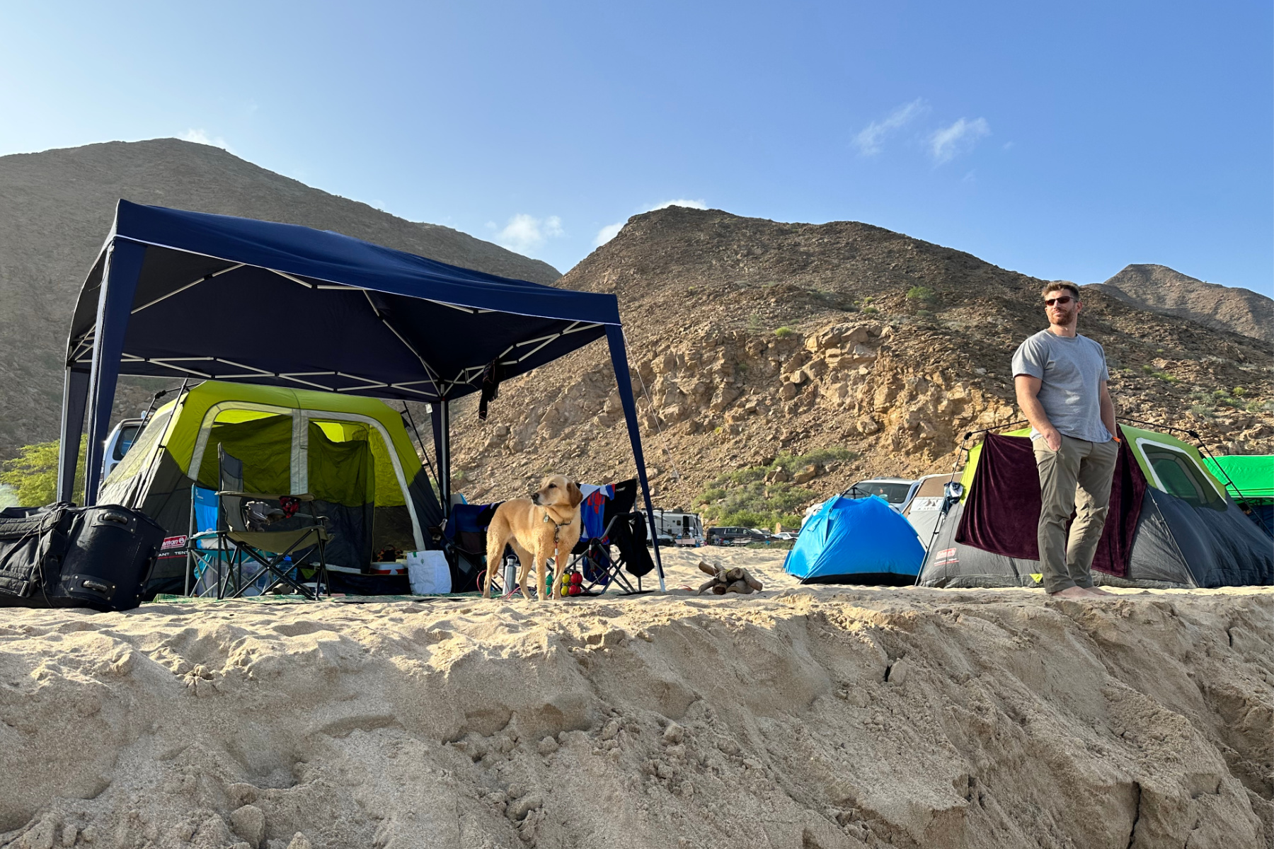 My husband and dog stood looking lout to sea from our tent and gazebo on Sifah Beach. There are mountains in the background