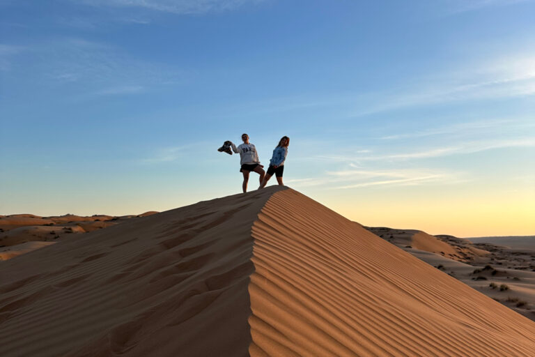 My daughters stood at the top of a sand dine at sun set