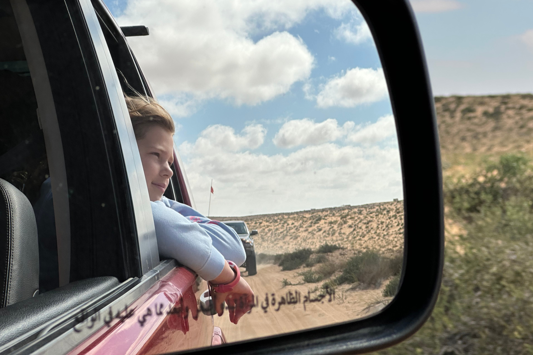 My daughter seen through our car wing mirror as we drive through the desert