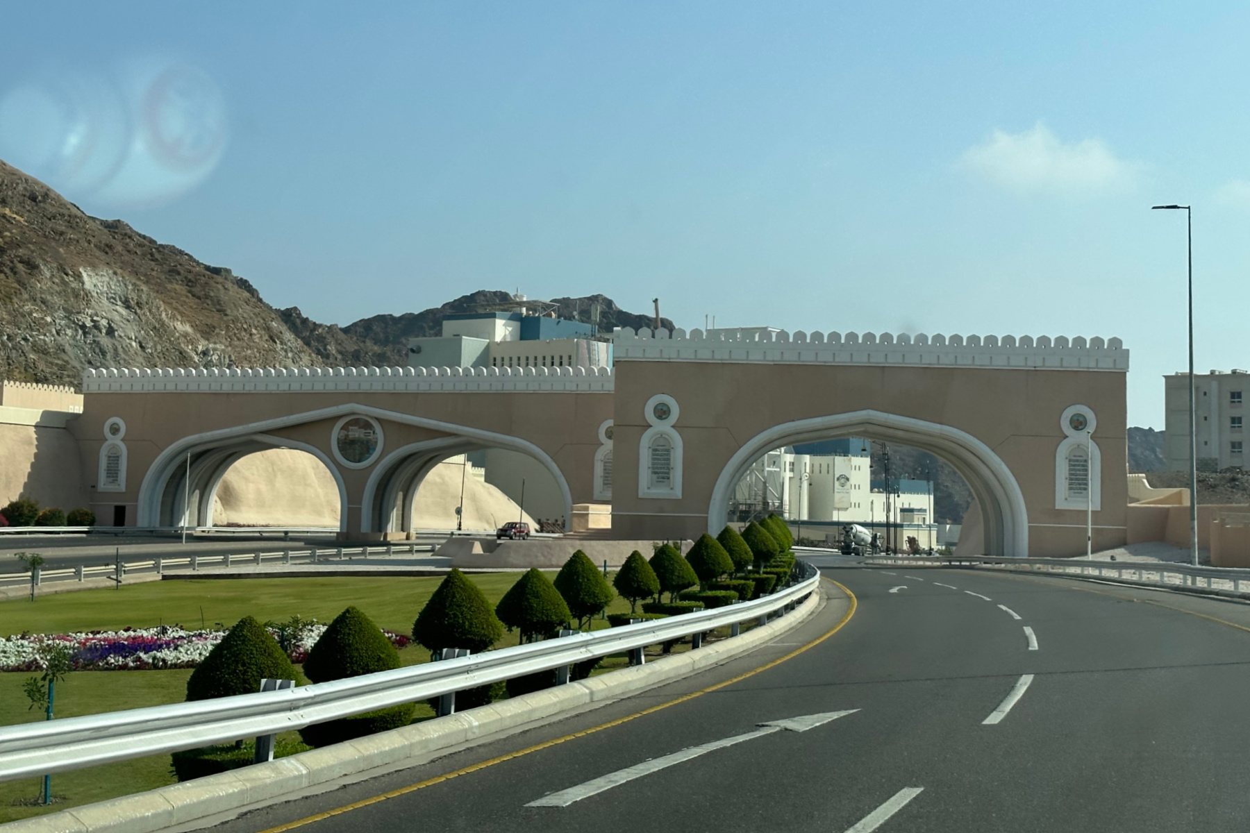 The old city gates on the way from modern Muscat into Muttrah. They have battlement at the top and arches through which the modern roads travel