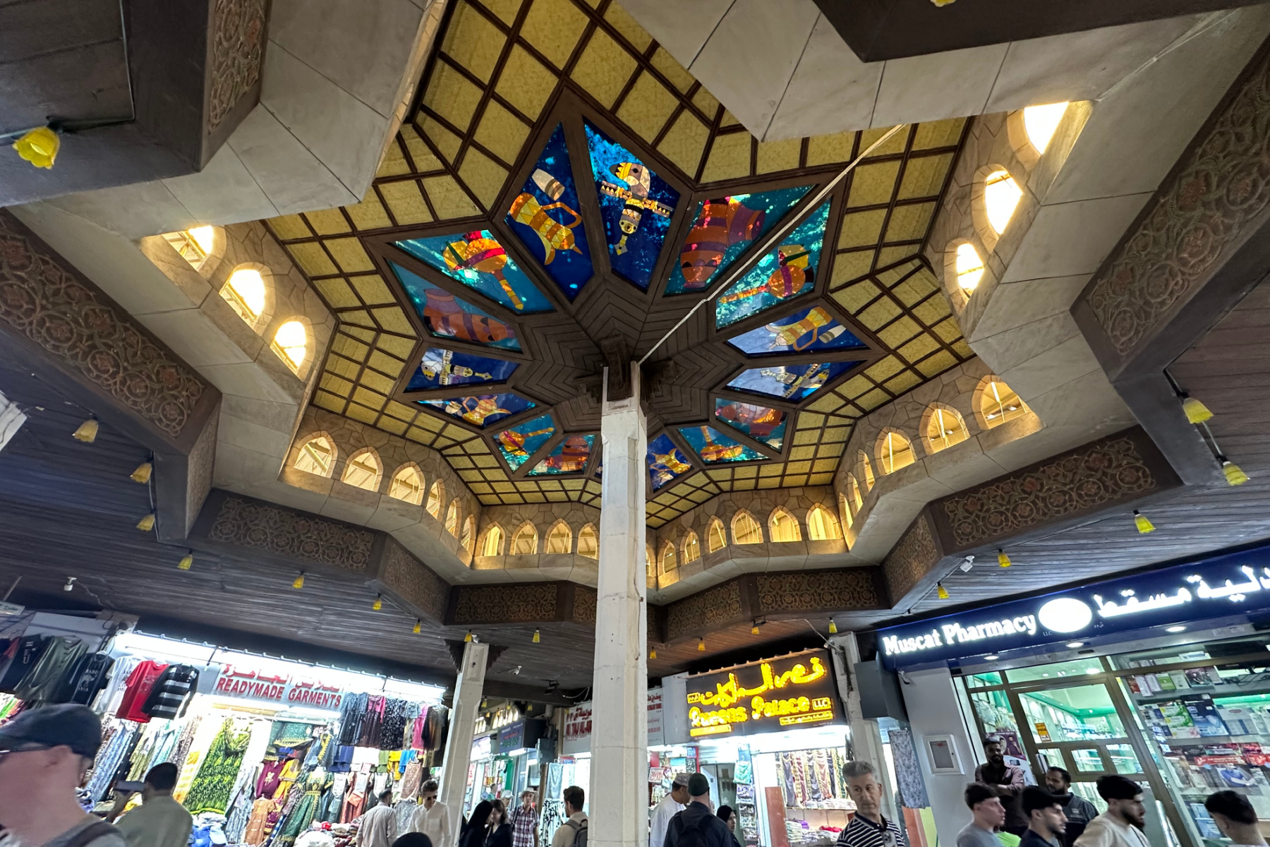 The stained glass ceiling in one of the courtyards of Muttrah Souq. The souq is bustling with people below